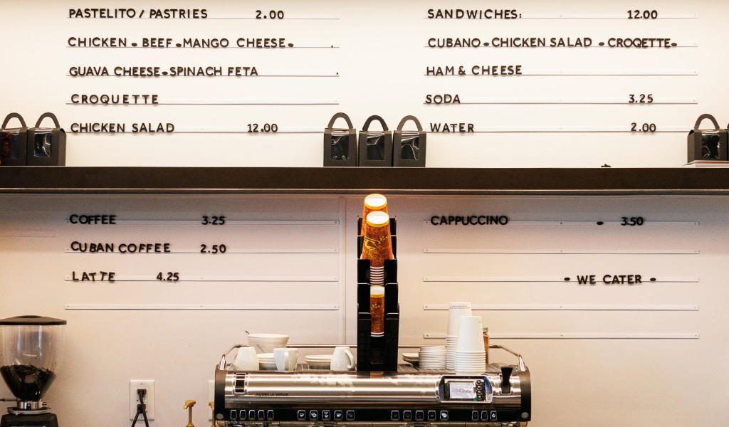 Coffee menu on the wall at Social Cafe in San Francisco, with coffee cups and espresso machine in front